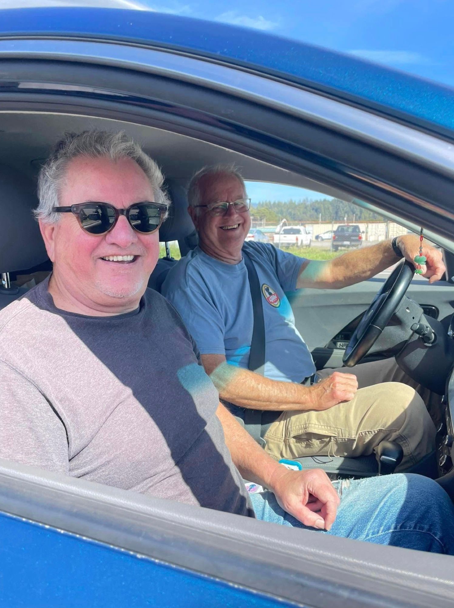 Two volunteer drivers grinning from the front seat of a car