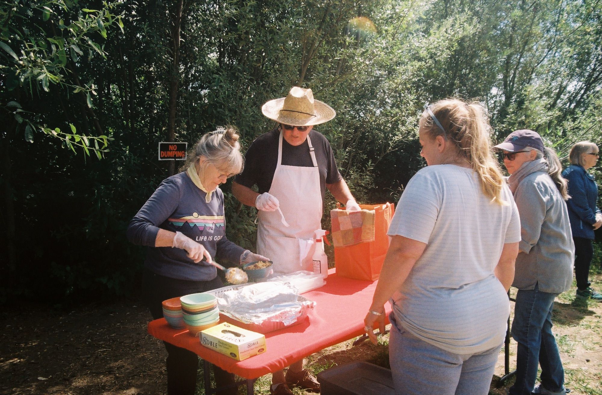 A volunteer crew serving a line of people at an outdoor table
