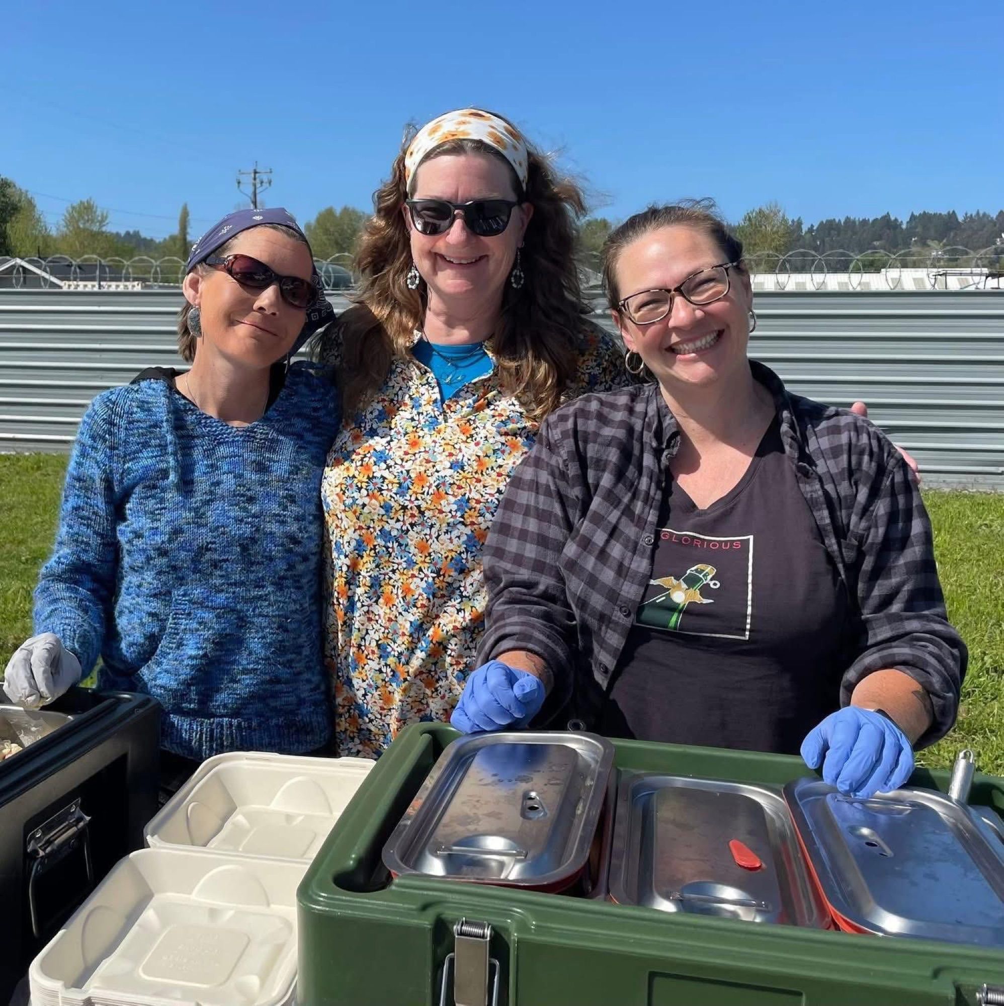 Three Soup's On volunteers smiling behind the food containers